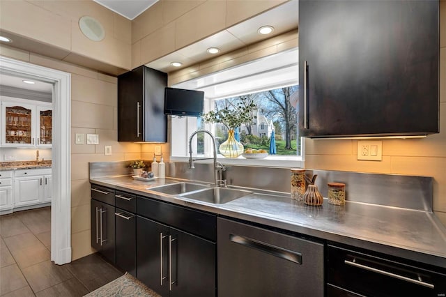 kitchen featuring stainless steel counters, stainless steel dishwasher, a sink, and white cabinets