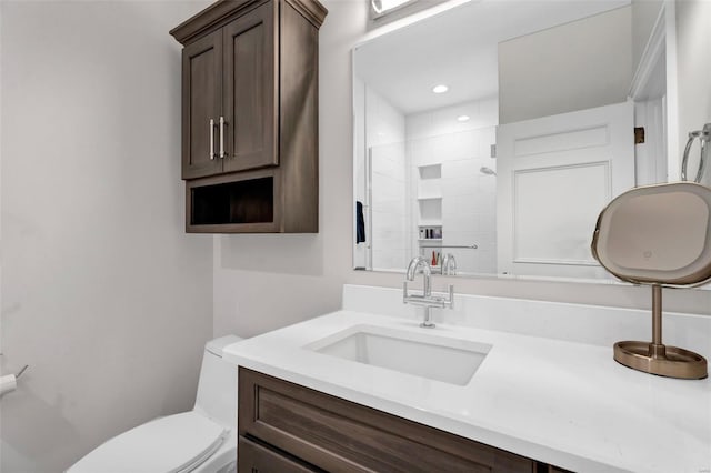 bathroom featuring toilet, vanity, a tile shower, and recessed lighting
