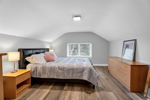 bedroom featuring lofted ceiling, wood finished floors, and baseboards