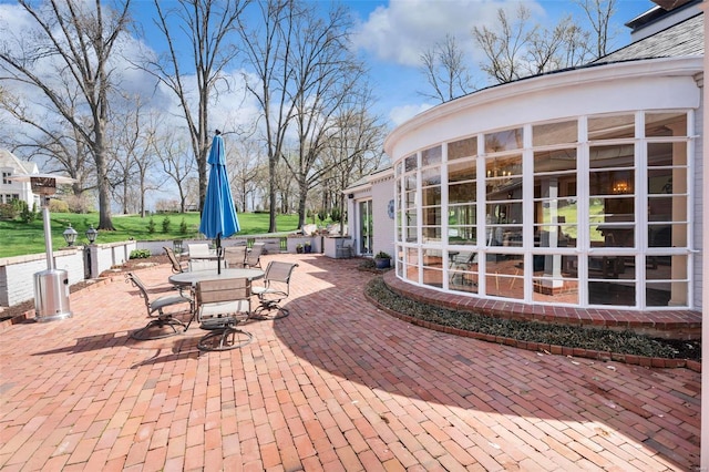 view of patio with outdoor dining area and a sunroom