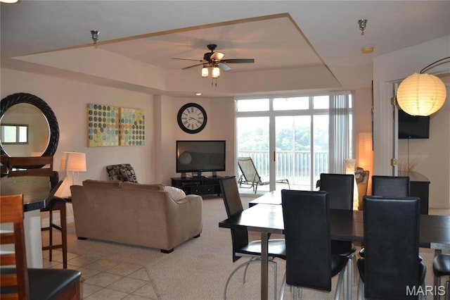 dining area with a raised ceiling, a ceiling fan, and light tile patterned flooring