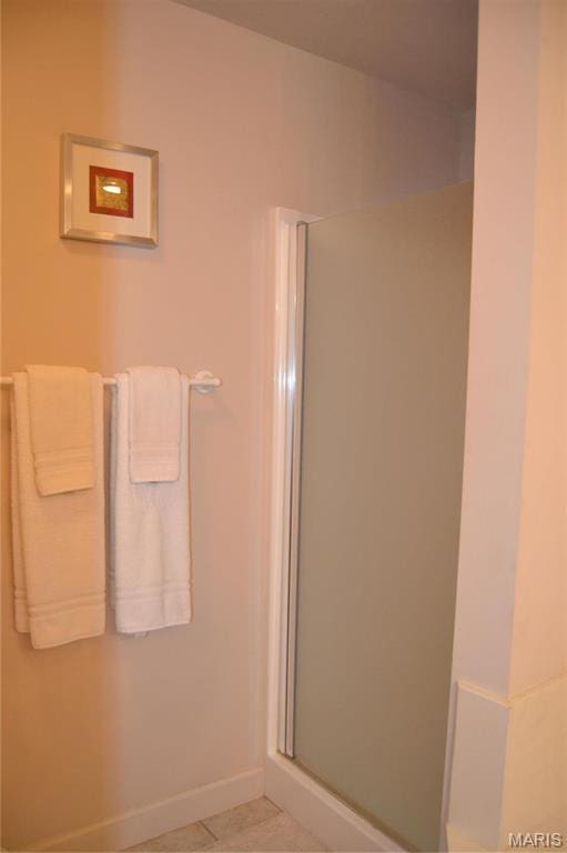 full bathroom with a stall shower and baseboards