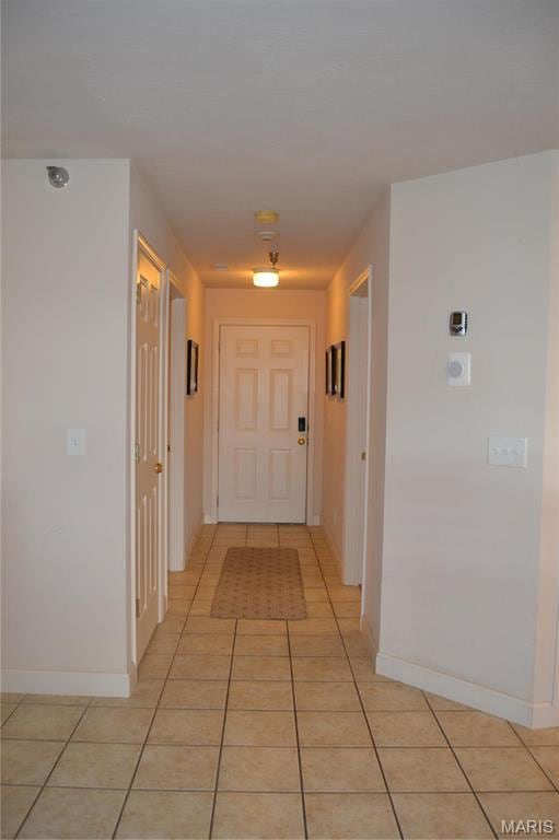 corridor with light tile patterned floors and baseboards