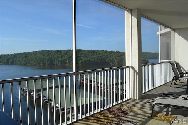 balcony featuring a water view and a wooded view