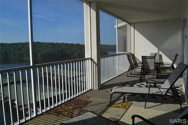 balcony featuring a water view and a view of trees