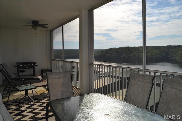 sunroom featuring a water view and a wooded view