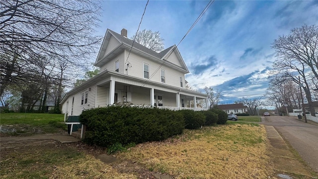 view of home's exterior featuring a porch and a chimney