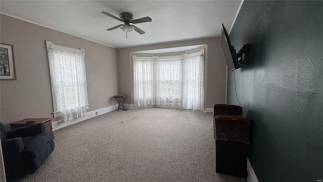 unfurnished living room with ceiling fan, healthy amount of natural light, carpet flooring, and baseboards