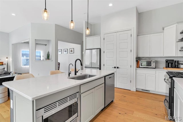 1154 Bloomfield Dr, Eureka, MO 63025 - kitchen featuring a sink, appliances with stainless steel finishes, light countertops, decorative light fixtures, and light wood finished floors
