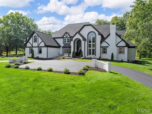 13516 Weston Park Dr, Saint Louis, MO 63131 - tudor house featuring a chimney, a front yard, stucco siding, and roof with shingles
