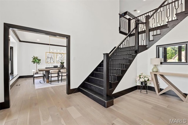 13516 Weston Park Dr, Saint Louis, MO 63131 - stairway with wood finished floors, baseboards, a towering ceiling, a chandelier, and recessed lighting