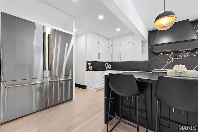 13516 Weston Park Dr, Saint Louis, MO 63131 - kitchen with high end refrigerator, dark countertops, white cabinetry, decorative backsplash, and light wood finished floors