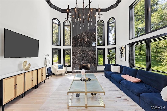 13516 Weston Park Dr, Saint Louis, MO 63131 - living area featuring a towering ceiling, ornamental molding, light wood-style flooring, a fireplace, and a chandelier