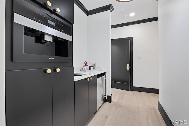 13516 Weston Park Dr, Saint Louis, MO 63131 - kitchen featuring dark cabinetry, light countertops, light wood-type flooring, ornamental molding, and wall oven