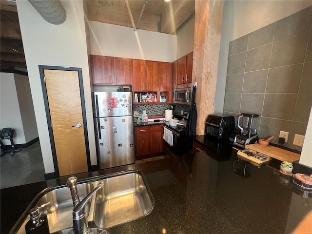 1113 Washington Ave Unit 510, Saint Louis, MO 63101 - kitchen featuring stainless steel appliances, dark countertops, tasteful backsplash, brown cabinetry, and a towering ceiling