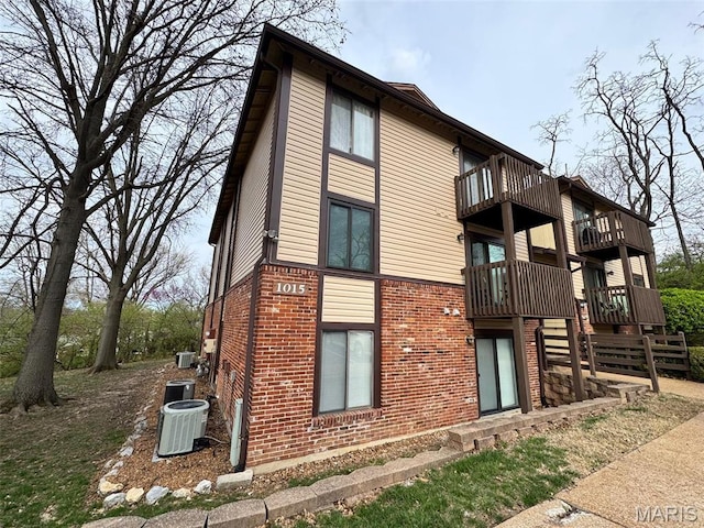 1015 Adworth Dr Unit F, Saint Louis, MO 63125 - view of property exterior with a balcony, brick siding, and central AC unit