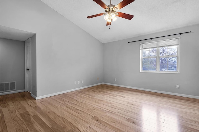 empty room with vaulted ceiling, a ceiling fan, light wood finished floors, baseboards, and a textured ceiling
