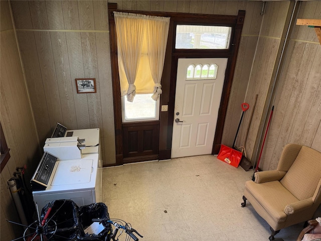 foyer with wood walls, tile patterned floors, and washing machine and dryer
