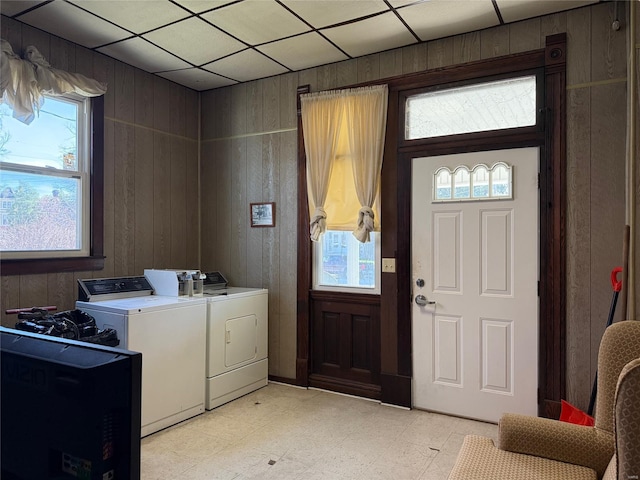 clothes washing area with independent washer and dryer, wood walls, and light floors