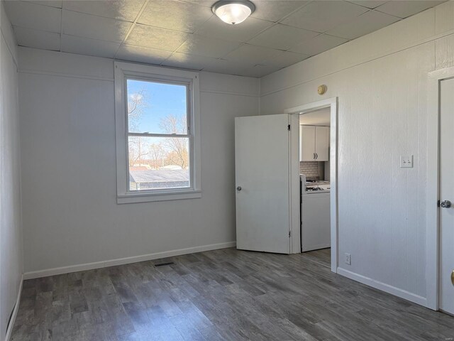 unfurnished room with wood finished floors, baseboards, and a drop ceiling
