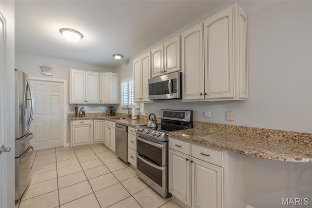 1005 Highland Estates Dr, Wentzville, MO 63385 - kitchen with appliances with stainless steel finishes, a sink, light tile patterned floors, and light stone counters