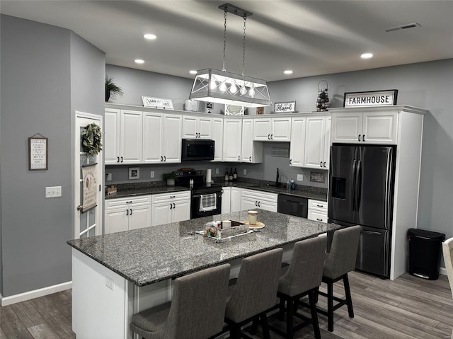 25371 Audrain Road 808, Mexico, MO 65265 - kitchen with black appliances, white cabinets, a kitchen island, a breakfast bar area, and recessed lighting