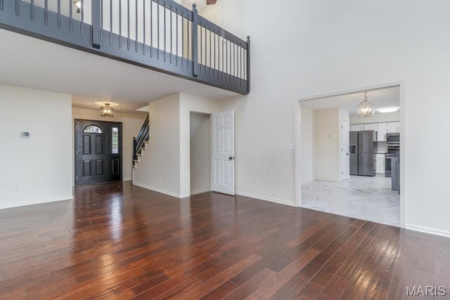 212 Tremont Dr, Waynesville, MO 65583 - unfurnished living room featuring a high ceiling, hardwood / wood-style flooring, a chandelier, baseboards, and stairway