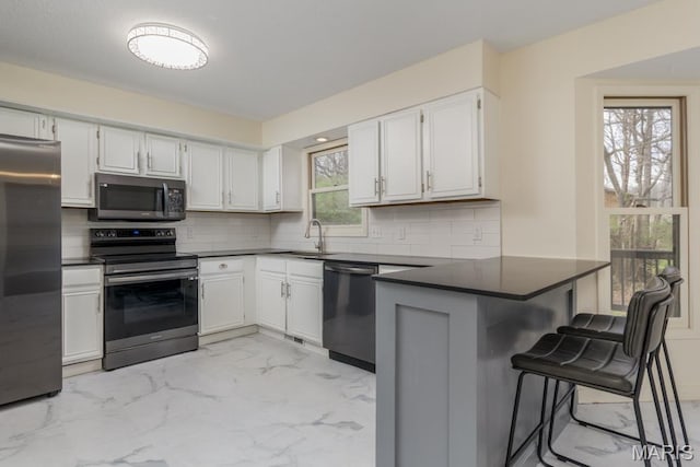 212 Tremont Dr, Waynesville, MO 65583 - kitchen with appliances with stainless steel finishes, dark countertops, a peninsula, and backsplash