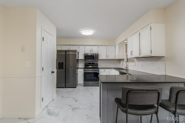 212 Tremont Dr, Waynesville, MO 65583 - kitchen with appliances with stainless steel finishes, a peninsula, light marble finish flooring, dark countertops, and backsplash