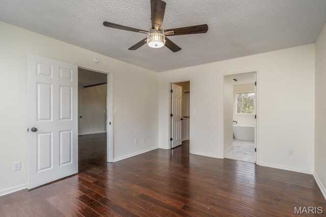 212 Tremont Dr, Waynesville, MO 65583 - unfurnished bedroom featuring wood finished floors, a textured ceiling, a spacious closet, baseboards, and connected bathroom