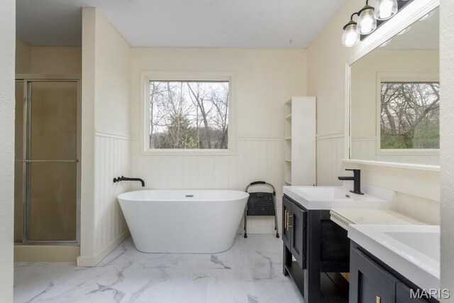 212 Tremont Dr, Waynesville, MO 65583 - bathroom with marble look tile flooring, wainscoting, two vanities, a stall shower, and plenty of natural light