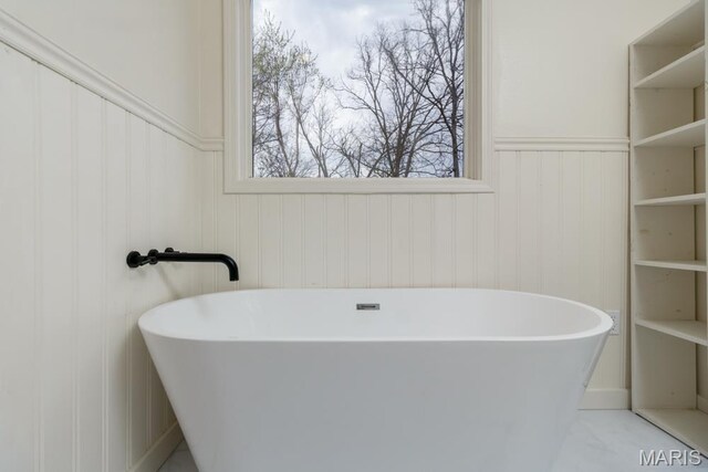 212 Tremont Dr, Waynesville, MO 65583 - bathroom featuring a freestanding bath, a wainscoted wall, and a decorative wall