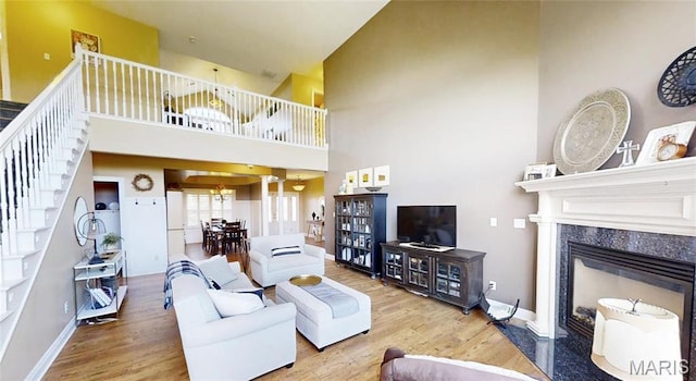 living area featuring wood finished floors, stairs, a high ceiling, a fireplace, and baseboards