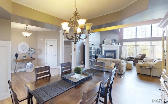dining room with wood finished floors, a chandelier, a glass covered fireplace, crown molding, and baseboards