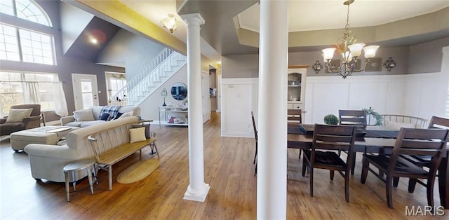 dining room with plenty of natural light, stairway, a decorative wall, ornate columns, and a wainscoted wall