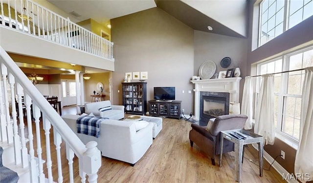living room featuring a high ceiling, wood finished floors, a chandelier, and a premium fireplace