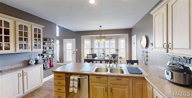 kitchen featuring a sink, stainless steel dishwasher, glass insert cabinets, light countertops, and a peninsula