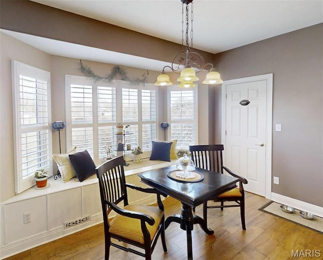 dining area with wood finished floors, a chandelier, and baseboards