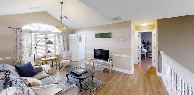 living area featuring light wood-style flooring, lofted ceiling, and baseboards