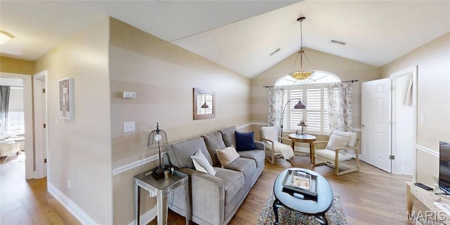 living area with light wood-style floors, lofted ceiling, and baseboards
