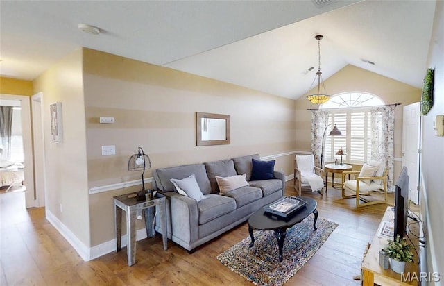 living area with light wood finished floors, lofted ceiling, and baseboards
