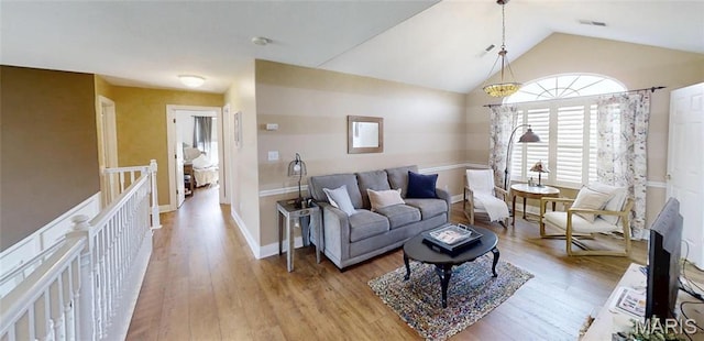 living room featuring light wood-style floors, vaulted ceiling, and baseboards
