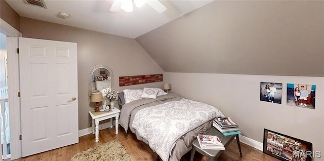 bedroom with wood finished floors, lofted ceiling, baseboards, and a ceiling fan