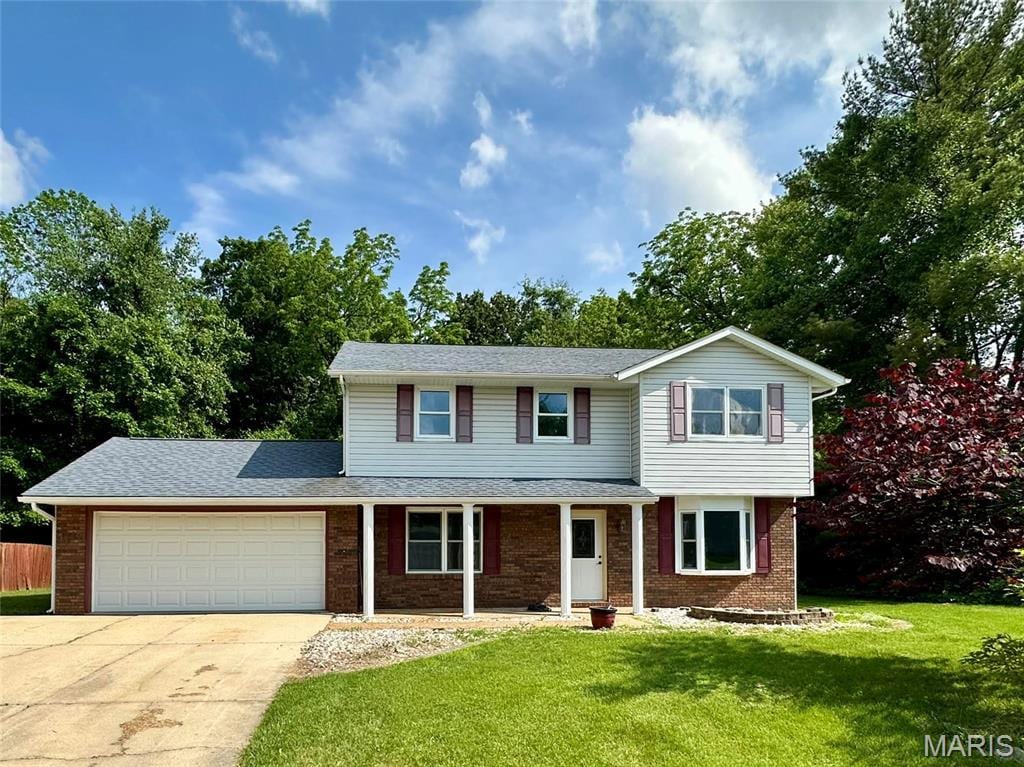953 Long Branch Rd, Troy, IL 62294 - traditional-style house featuring an attached garage, brick siding, concrete driveway, and covered porch