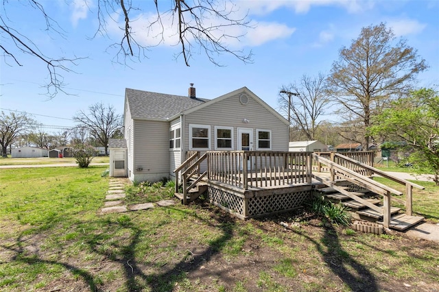 rear view of house featuring a deck, a chimney, and a yard