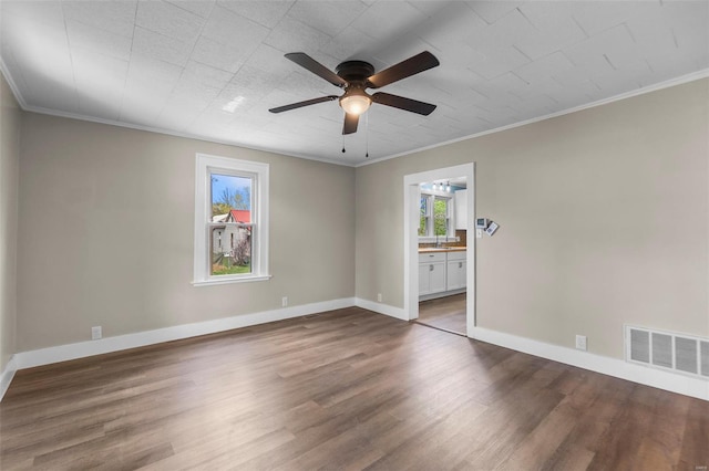 empty room featuring wood finished floors, ceiling fan, baseboards, and ornamental molding