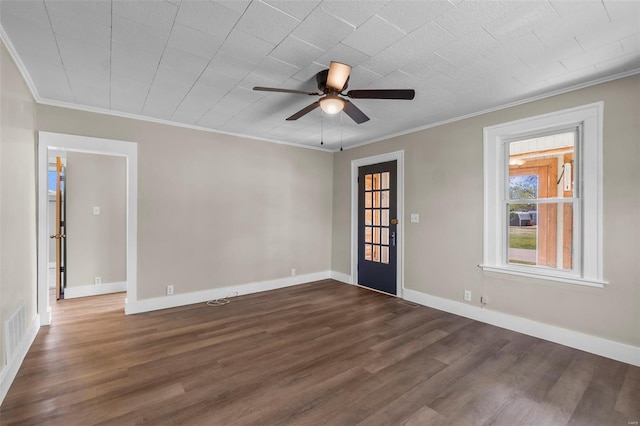 empty room with dark wood-style floors, a ceiling fan, crown molding, and baseboards