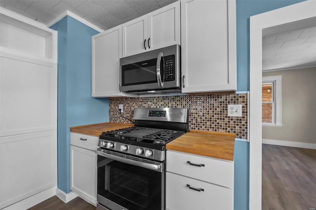 kitchen featuring wooden counters, stainless steel appliances, tasteful backsplash, dark wood-style flooring, and baseboards