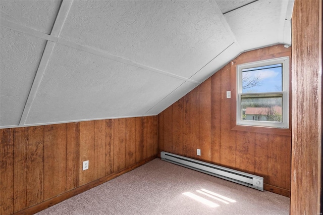 bonus room featuring a baseboard radiator, a textured ceiling, lofted ceiling, wood walls, and carpet floors