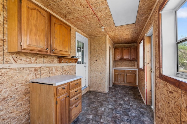 kitchen featuring light countertops, brown cabinetry, and a skylight